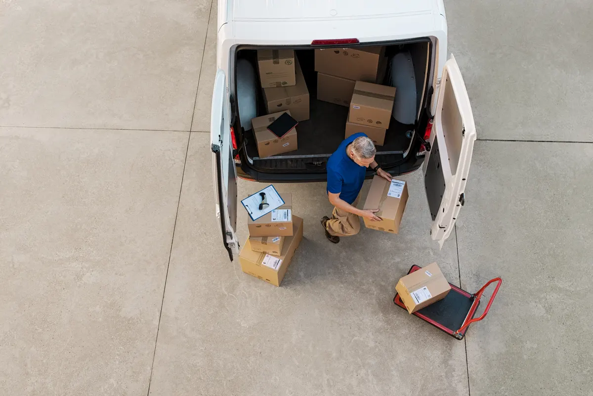 Zusteller entlädt Pakete aus einem Transporter von I.A. Transporte